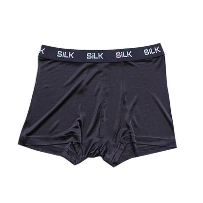 Man wearing loose-fit mid-waist shorts in navy blue silk fabric.