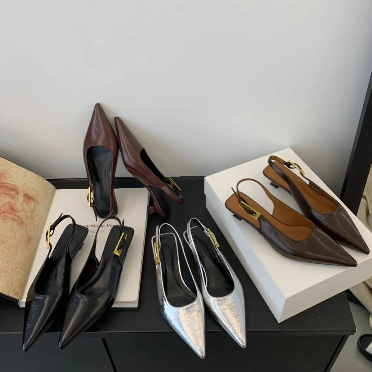 Women's black leather pointed toe shoes with low heel and thin strap.