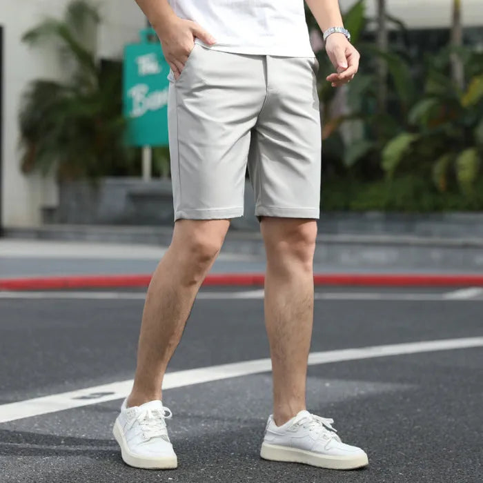 Man wearing loose-fit beige fifth pants with an elastic waistband, showcasing the mid-length casual style.