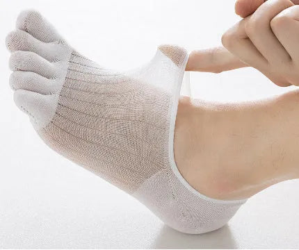 Pair of solid colour modal five-finger invisible socks on a wooden surface, showing toe separation and low-cut design.