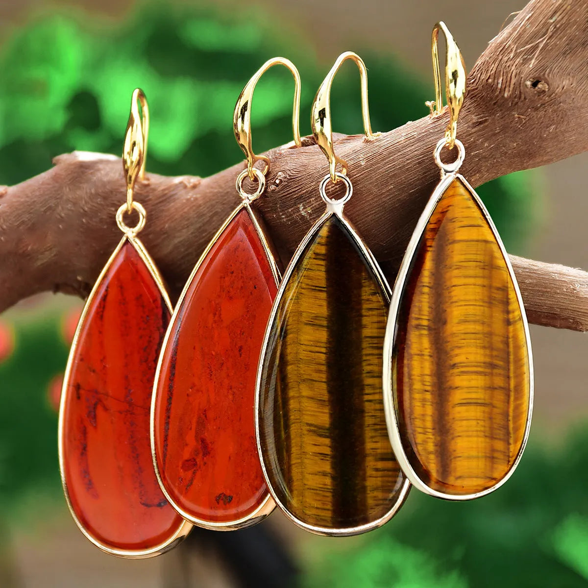 Handmade vintage long water drop earrings with tigereye stone and sterling silver hooks on a textured background.