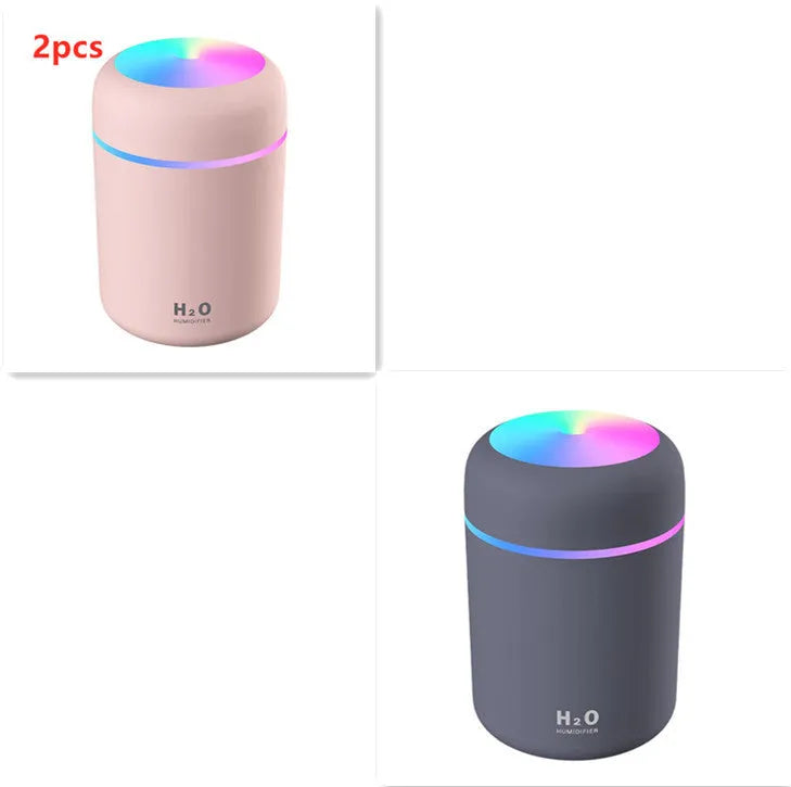 Pink USB desktop humidifier with LED lights and water tank on wooden desk