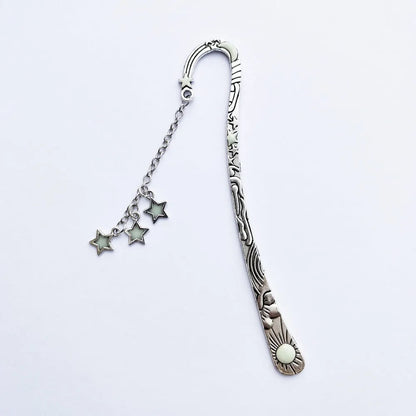 Retro five-pointed star glowing metal bookmark in ancient silver and bronze finishes on an open book.