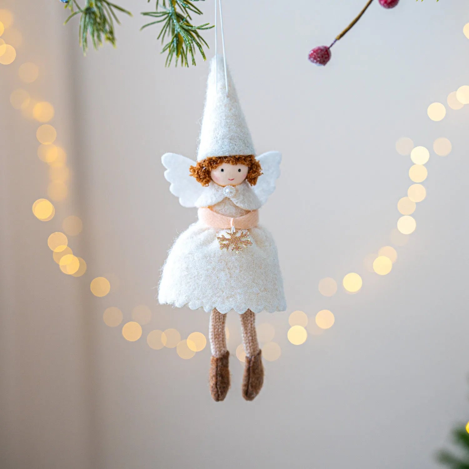 White and pink cloth felt Christmas angel skirt pendant ornament on a tree branch.