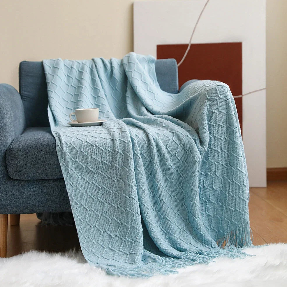 Nordic knitted blanket in beige colour showing open knit pattern on grey sofa