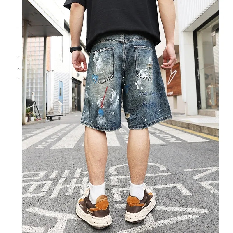 Blue men's jeans shorts with ripped distressed detailing and graffiti design, straight leg cut with zipper fly