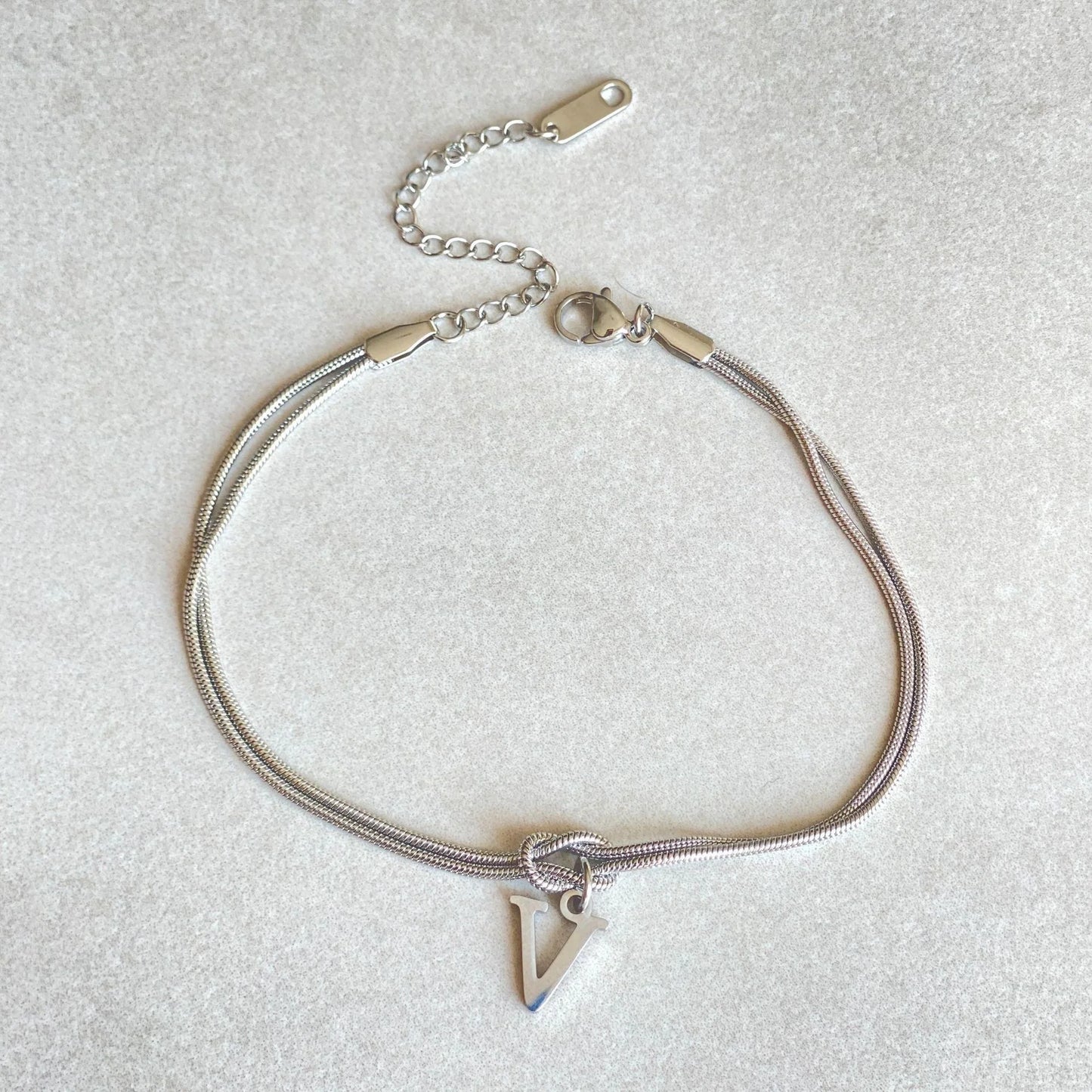 Elegant letter charm bracelets for women in gold and silver tones, featuring a delicate snake chain design and personalised letter charms.