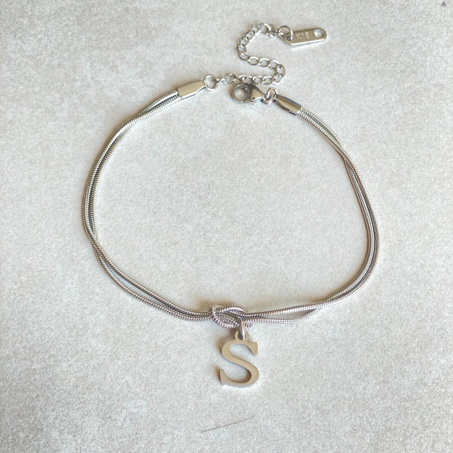 Elegant letter charm bracelets for women in gold and silver tones, featuring a delicate snake chain design and personalised letter charms.