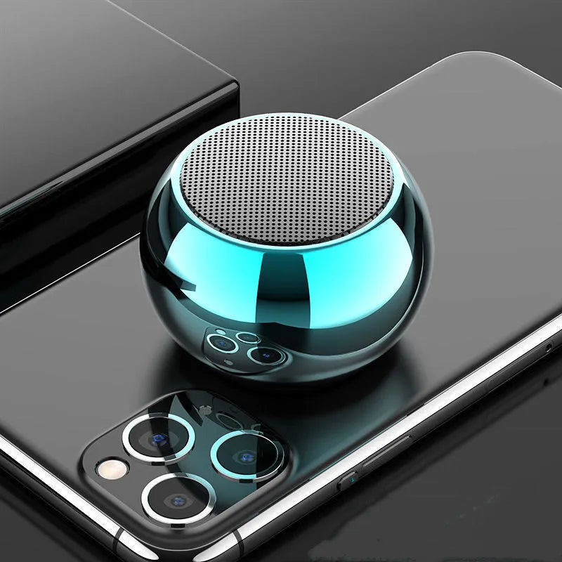 Small round aluminium Bluetooth speaker in gradient blue, showing compact size next to a USB cable.