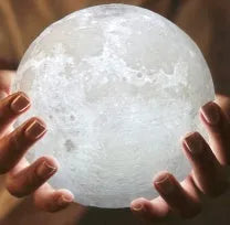 3D printed white moon lamp on a wooden holder, showing detailed crater texture and soft LED glow.