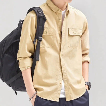 Man wearing a loose-fit grey cardigan-style overalls shirt with long sleeves.