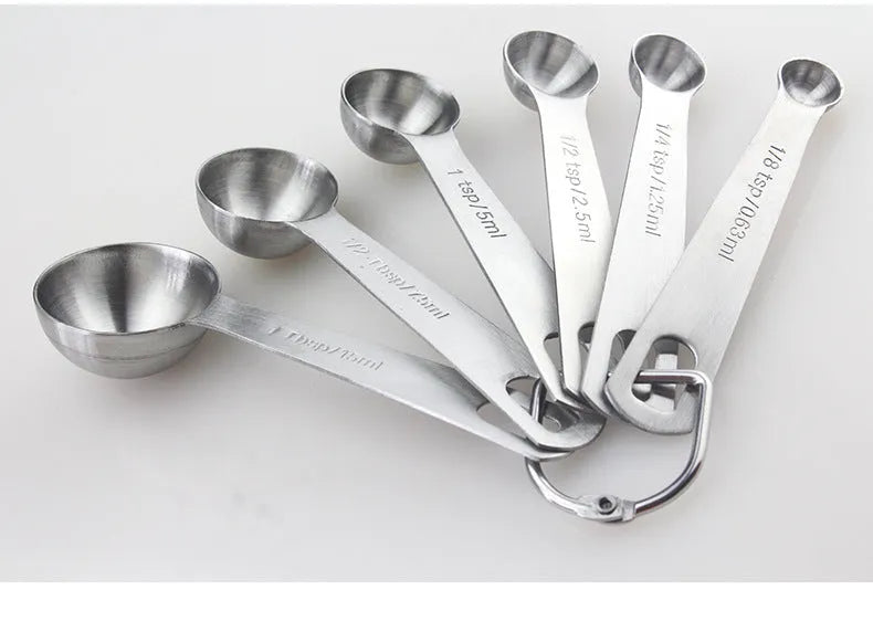 Set of six stainless steel measuring spoons connected by a silver D-ring, showing engraved measurement markings