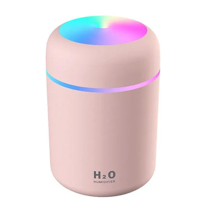 Pink USB desktop humidifier with LED lights and water tank on wooden desk