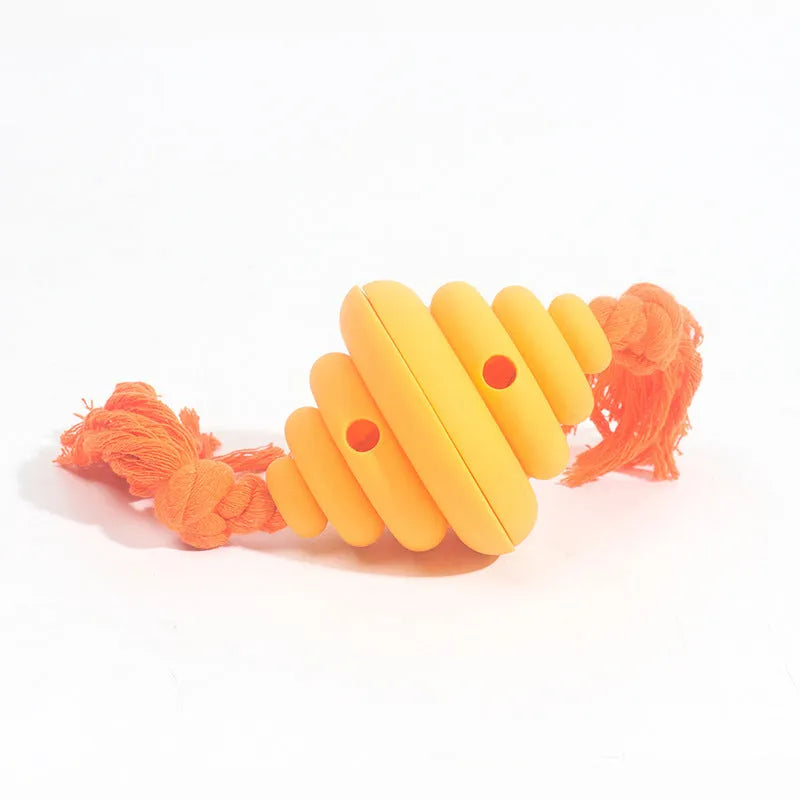 Green and yellow dog ball with attached knotted rope chew and feeder toy on grass.