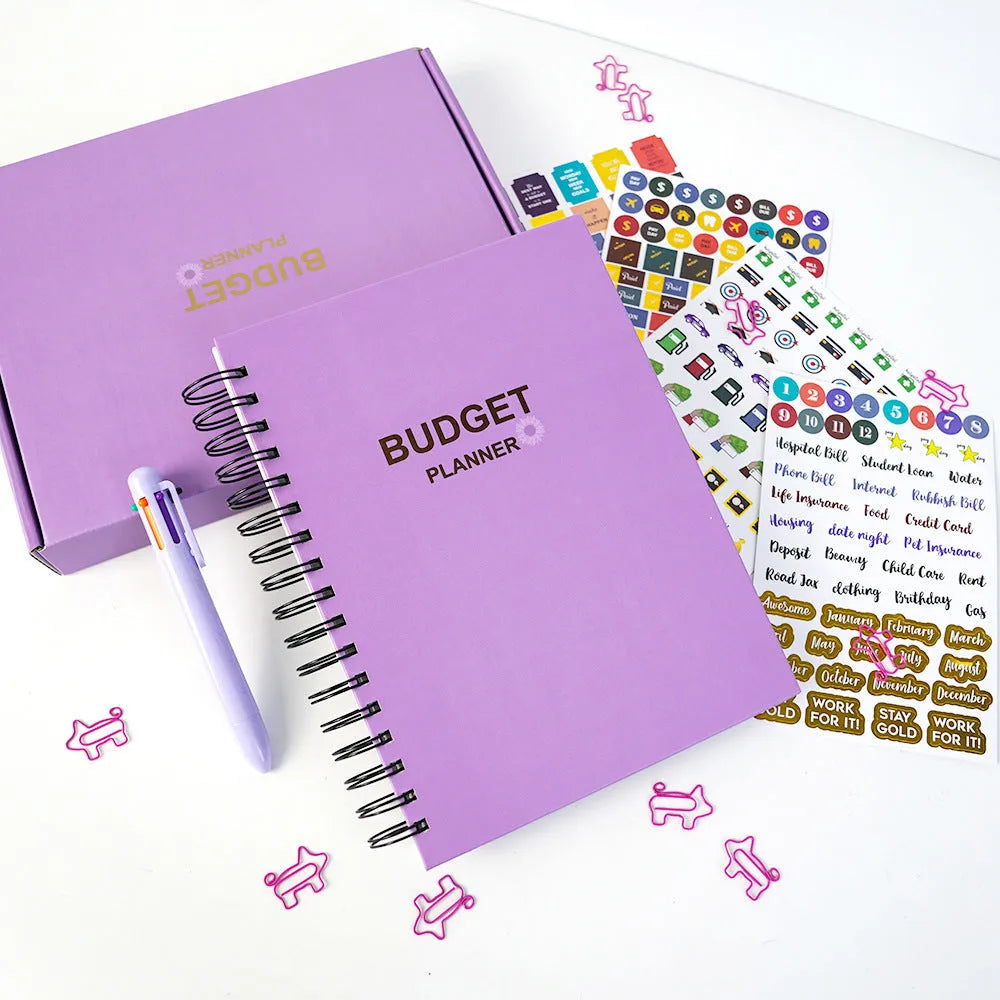 Purple coil-bound A5 budget notebook with pen, stickers and paper clips for financial planning