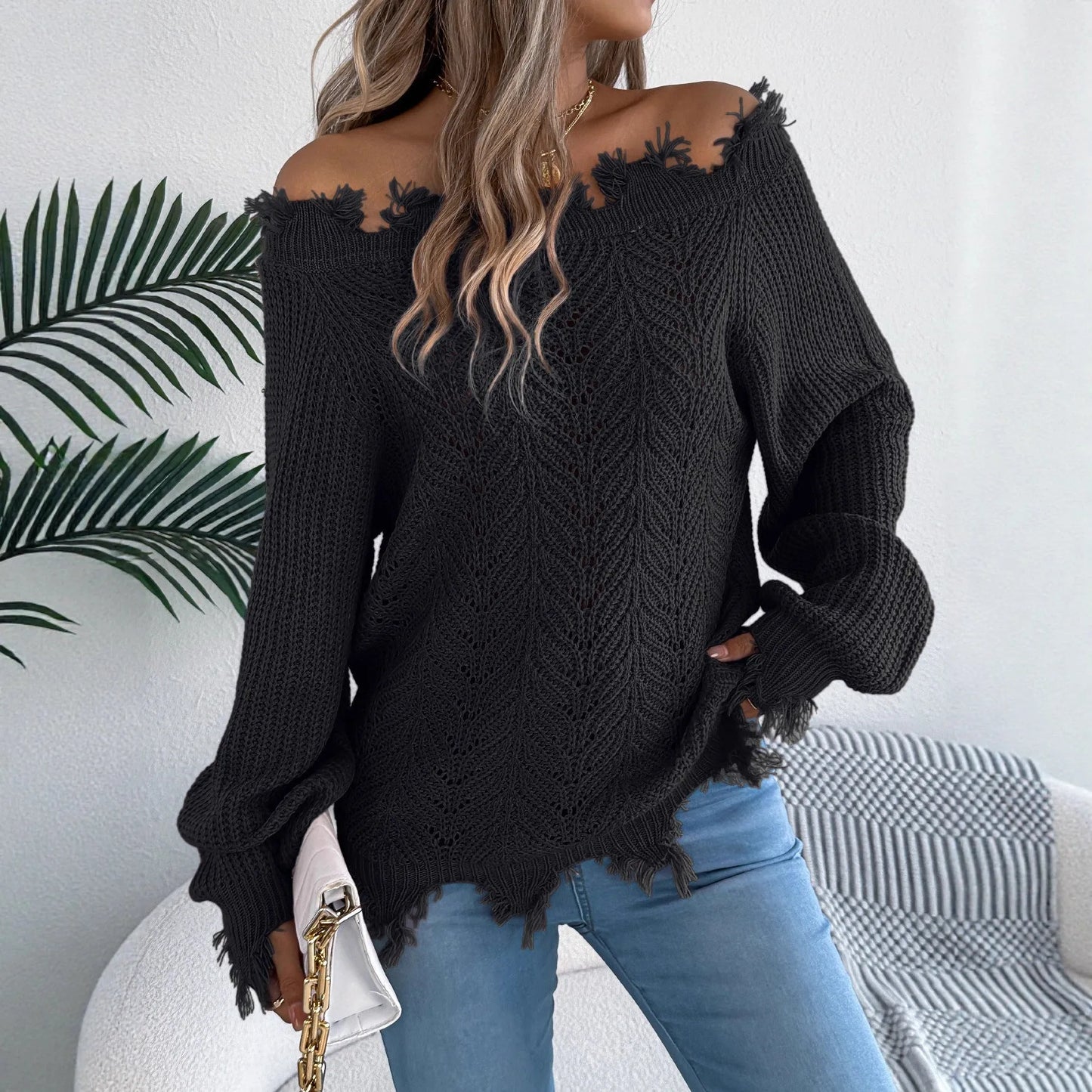 Women's black off-the-shoulder pullover sweater with hollow-out long sleeves on a hanger.