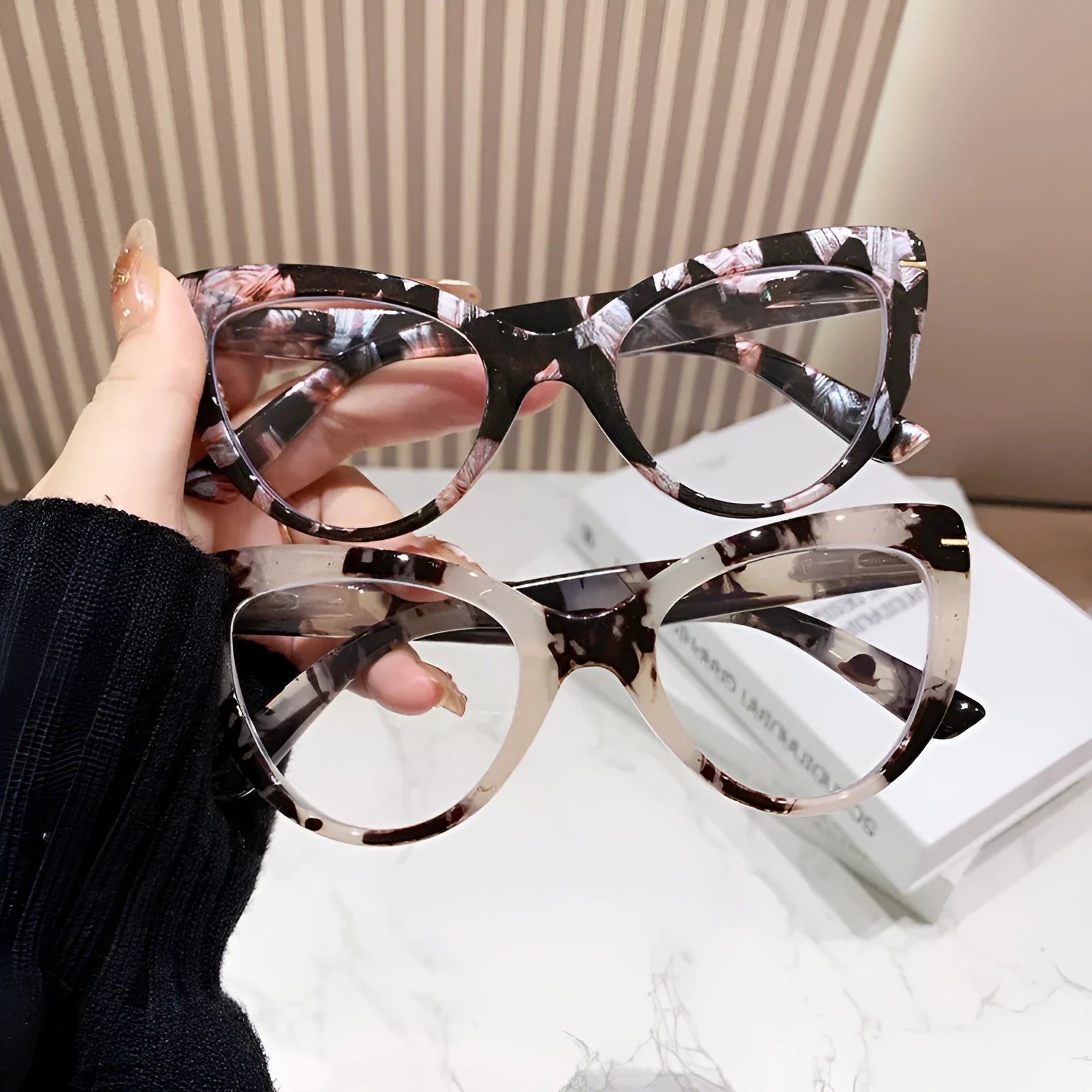 Women's black floral cat's eye reading glasses with large frames on a wooden table.