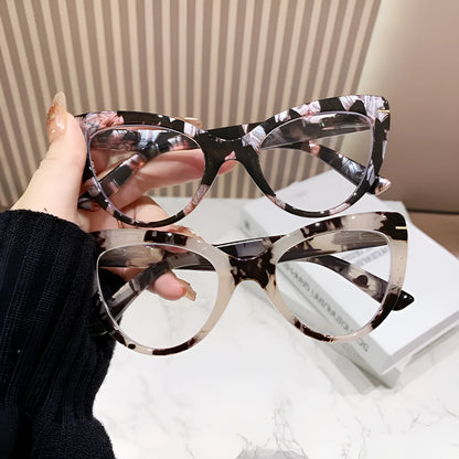 Women's black floral cat's eye reading glasses with large frames on a wooden table.