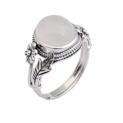 Adjustable open-mouth copper vintage ring with U-shape and antiqued white chalcedony-style finish on a wooden surface.