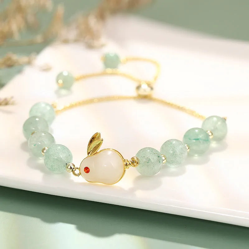 Adjustable rabbit charm bracelet with natural stone beads and gold plated details on a wrist.