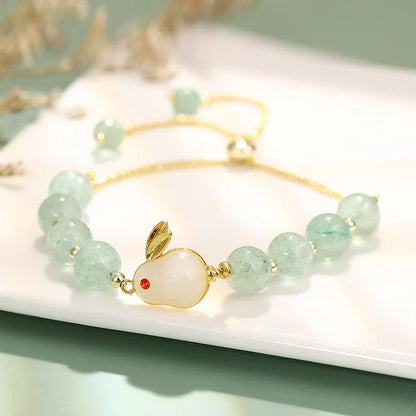 Adjustable rabbit charm bracelet with natural stone beads and gold plated details on a wrist.