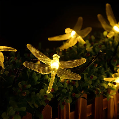 Solar-powered dragonfly string lights with 30 warm white LEDs in garden setting