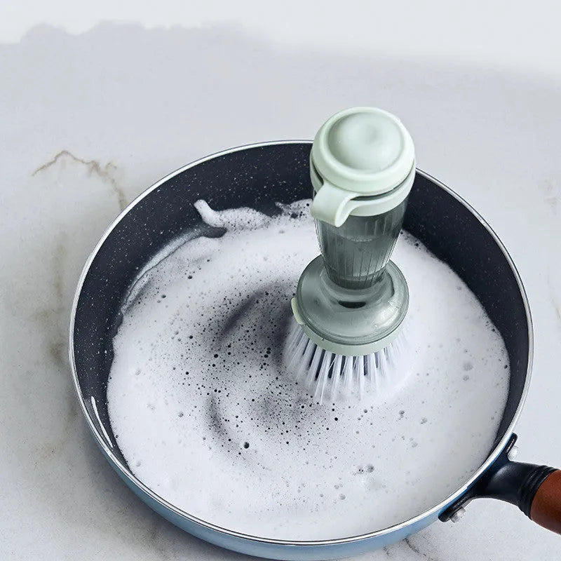 Milk white and mint green pot scrub brush with a soap dispenser handle and replaceable non-scratch bristles.