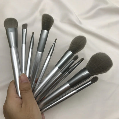 10 makeup brushes with moonlight silver finish and wooden handles beside PU brush bag