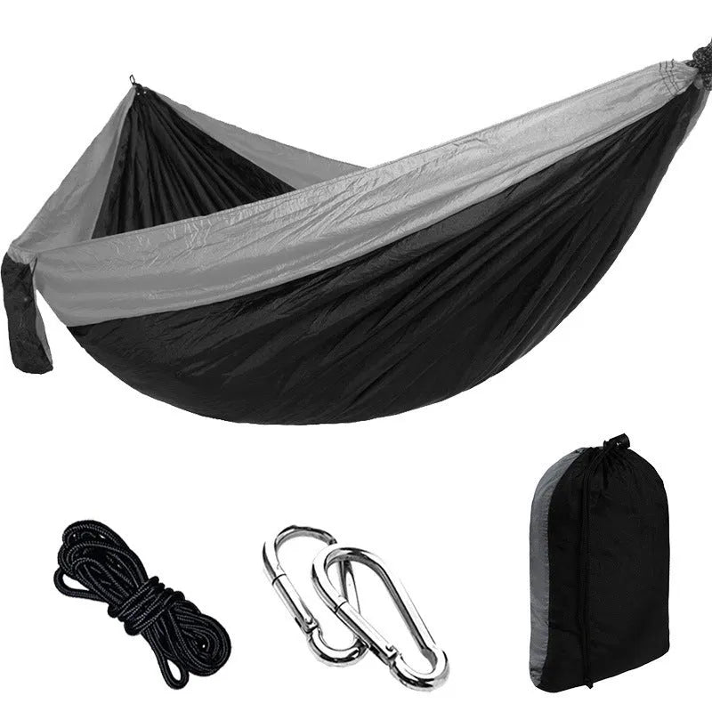 Parachute cloth double camping hammock in chosen colour, with black buckles and round ropes on a tree.