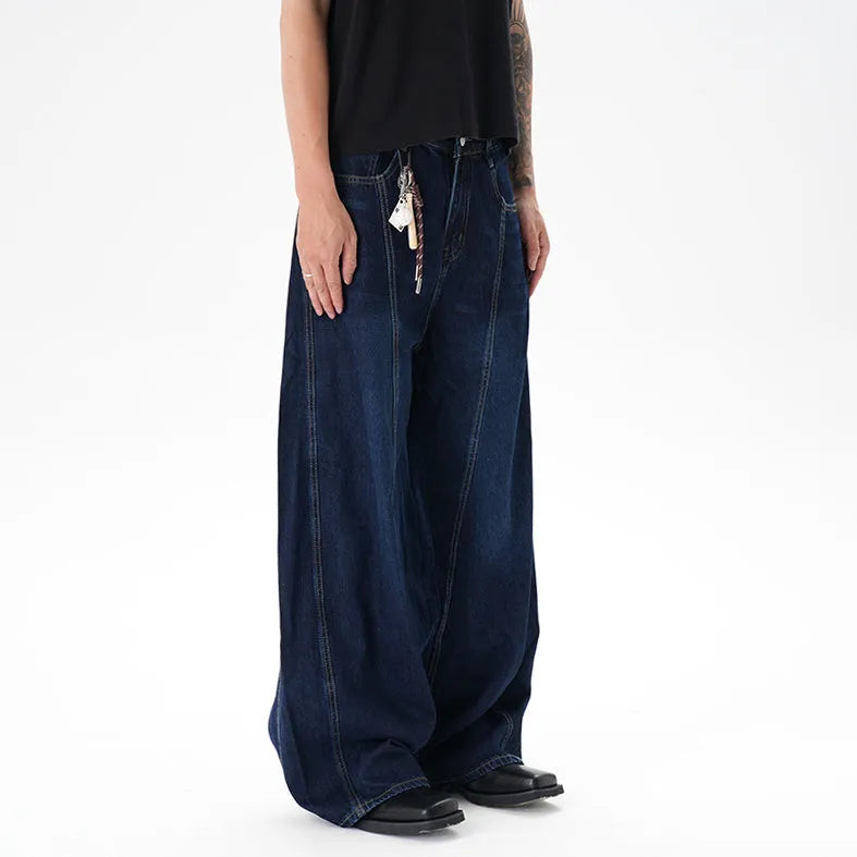 Dark blue distressed wide leg Machete jeans laid flat, showing washed denim texture.
