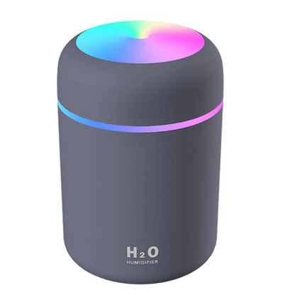 Pink USB desktop humidifier with LED lights and water tank on wooden desk