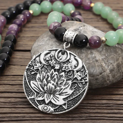 Long stone bead necklace with alloy lotus pendant and matching bracelet set on a background.