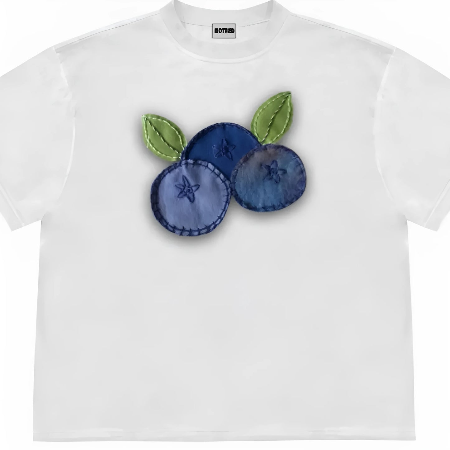 A loose-fit blueberry patchwork short-sleeve T-shirt on a hanger, showing plant and flower designs.