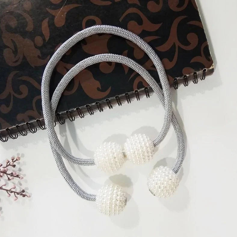 Magnetic curtain tiebacks with white pearl beads and fabric loops holding gathered curtain