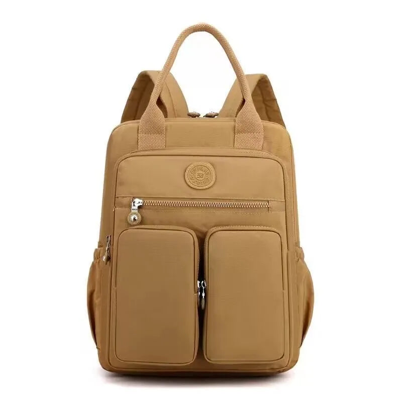 Women's waterproof nylon travel backpack in grey, showing front external pocket and organisational interior.