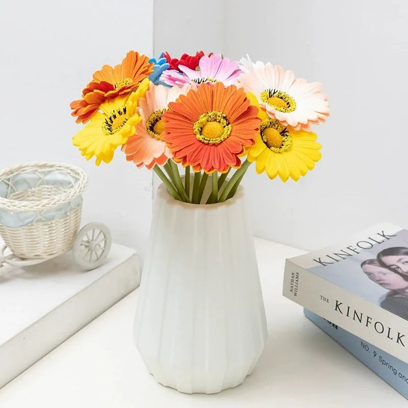 Silk artificial flower bouquet in a white polyurethane pot on a wooden table.
