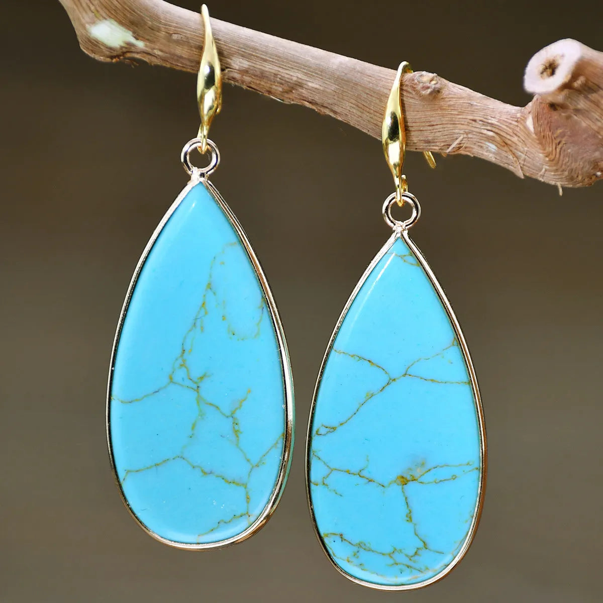 Handmade vintage long water drop earrings with tigereye stone and sterling silver hooks on a textured background.