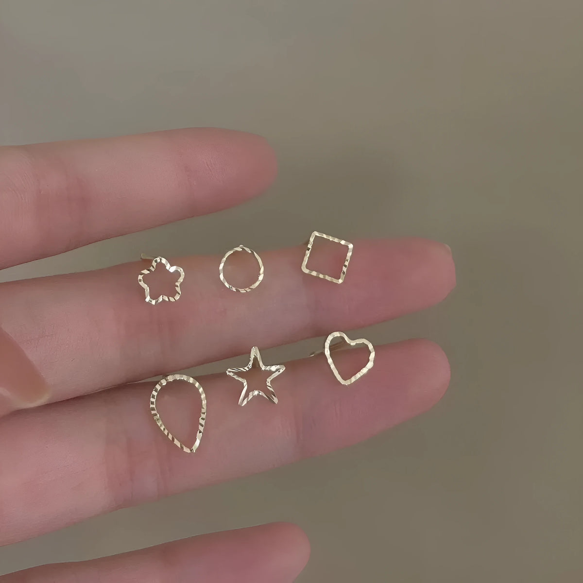 Pair of small spiral geometric ear studs with gold hollow thread finish in mixed material, shown in eight shape options.