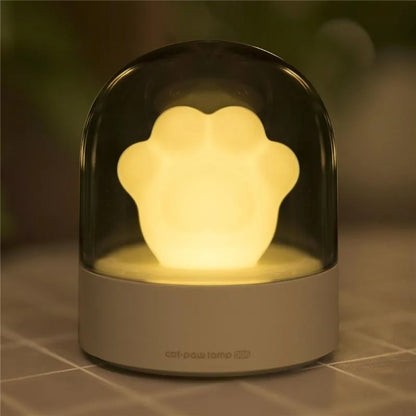 Grey cat paw night light with USB cable on a wooden desk, showing soft glow and detailed paw sculpt.