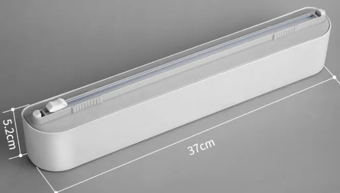 Black plastic cling film cutter and dispenser unit mounted on a refrigerator door.