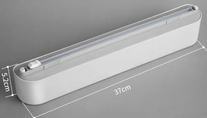 Black plastic cling film cutter and dispenser unit mounted on a refrigerator door.