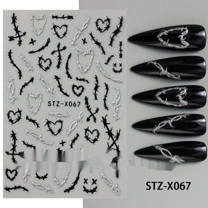 Assortment of black and silver nail sticker designs including cartoon and French tip patterns on a plastic sheet.