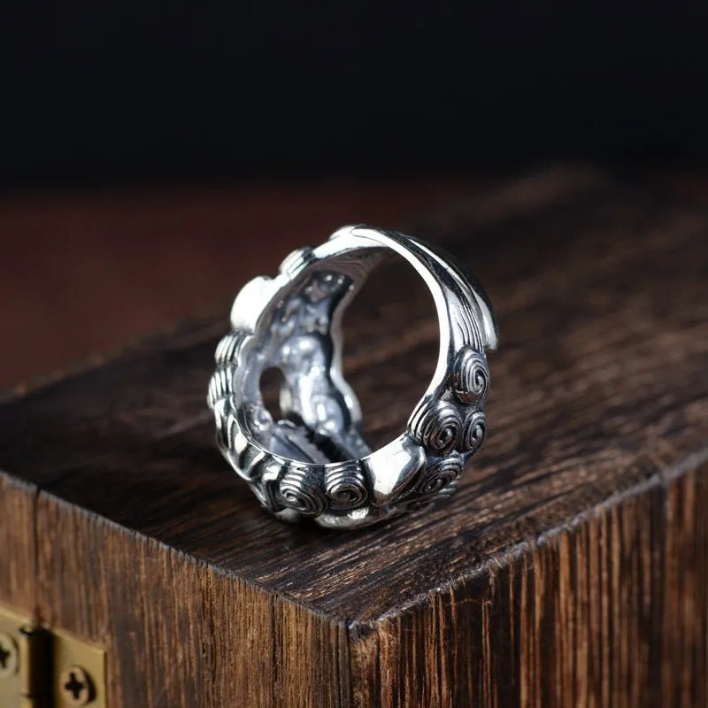 Domineering open ring with engraved animal pattern on wide sterling silver band, shown on a finger.