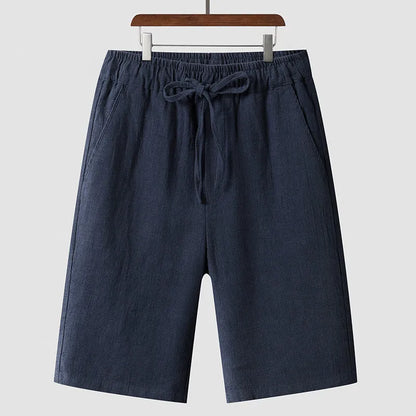 Men's beige linen casual shorts with a loose fit and elastic waistband on a neutral background.