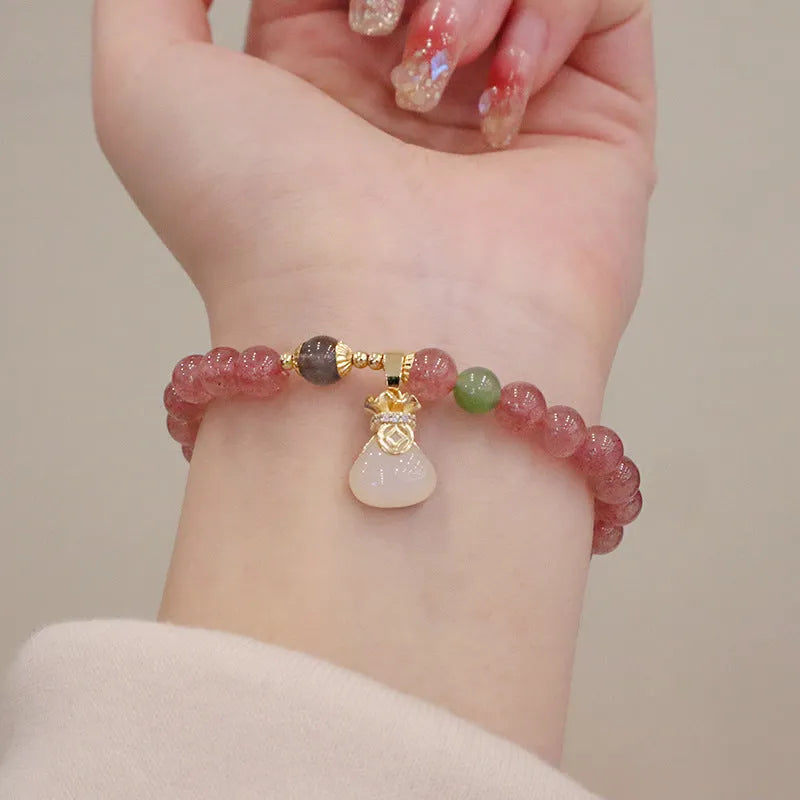 Natural strawberry quartz geometric bracelet with a small purse charm and silver safety buckle closure.