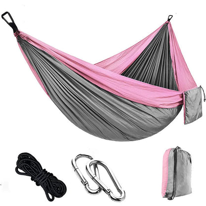 Parachute cloth double camping hammock in chosen colour, with black buckles and round ropes on a tree.