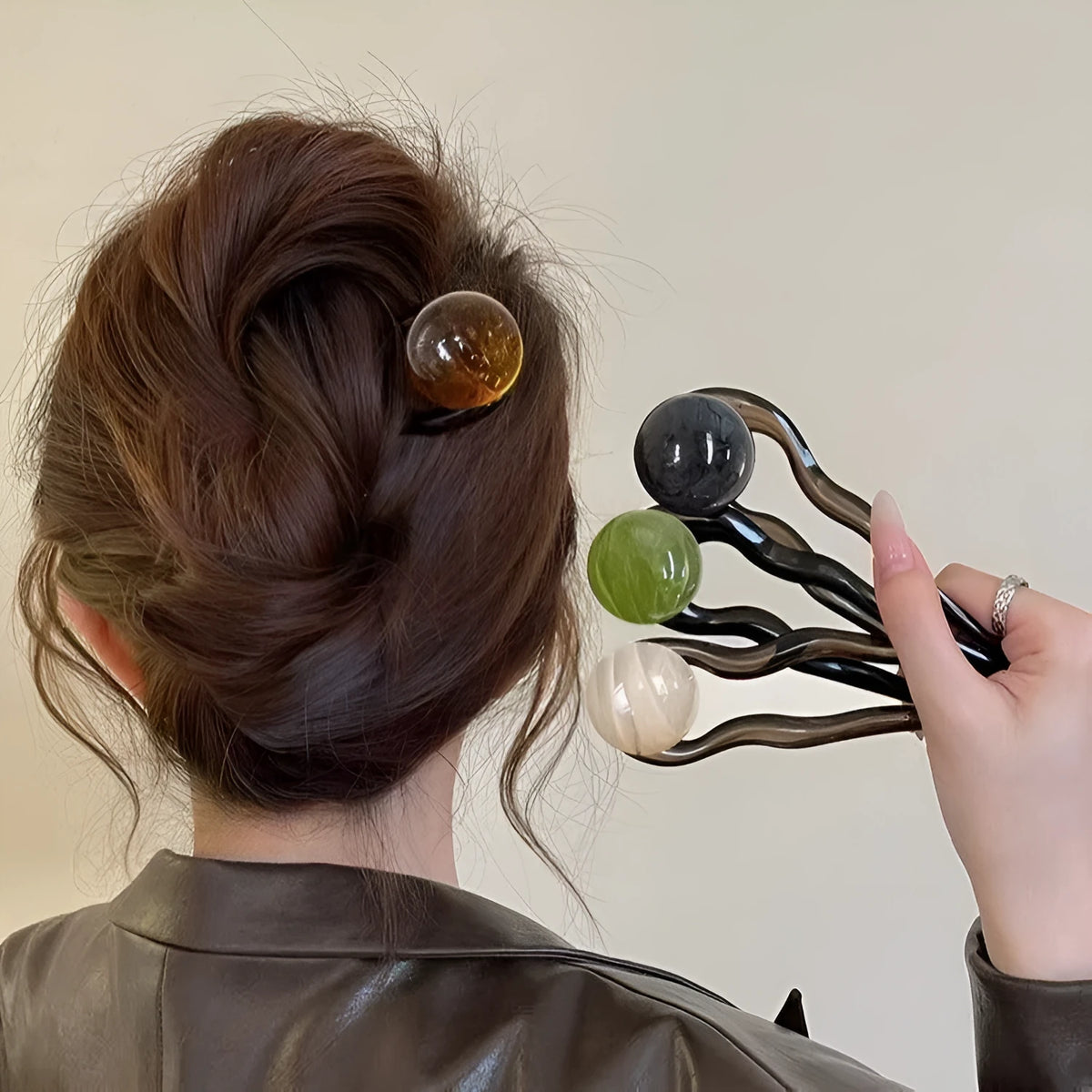 A set of U-shaped acrylic hair barrettes with a simple ball decoration in beige, caramel, and dark grey colours.