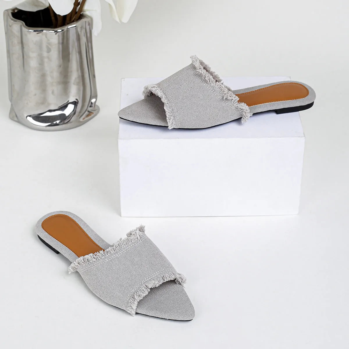 Women's denim flat slippers with tassel detail in apricot colour, showing leather lining.