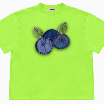 A loose-fit blueberry patchwork short-sleeve T-shirt on a hanger, showing plant and flower designs.