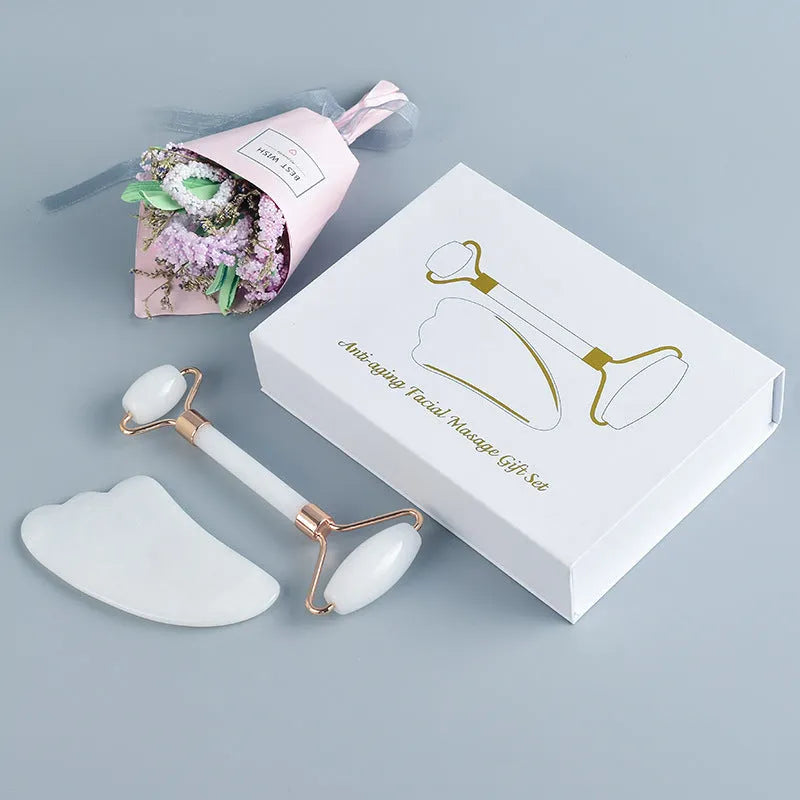 White jade facial roller with double-headed claw design and matching scraping board on dark surface